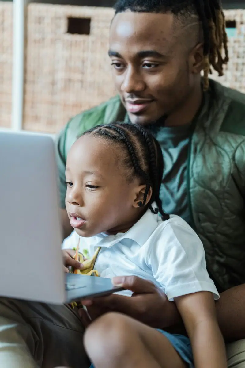 Dad holding his toddler while using a laptop