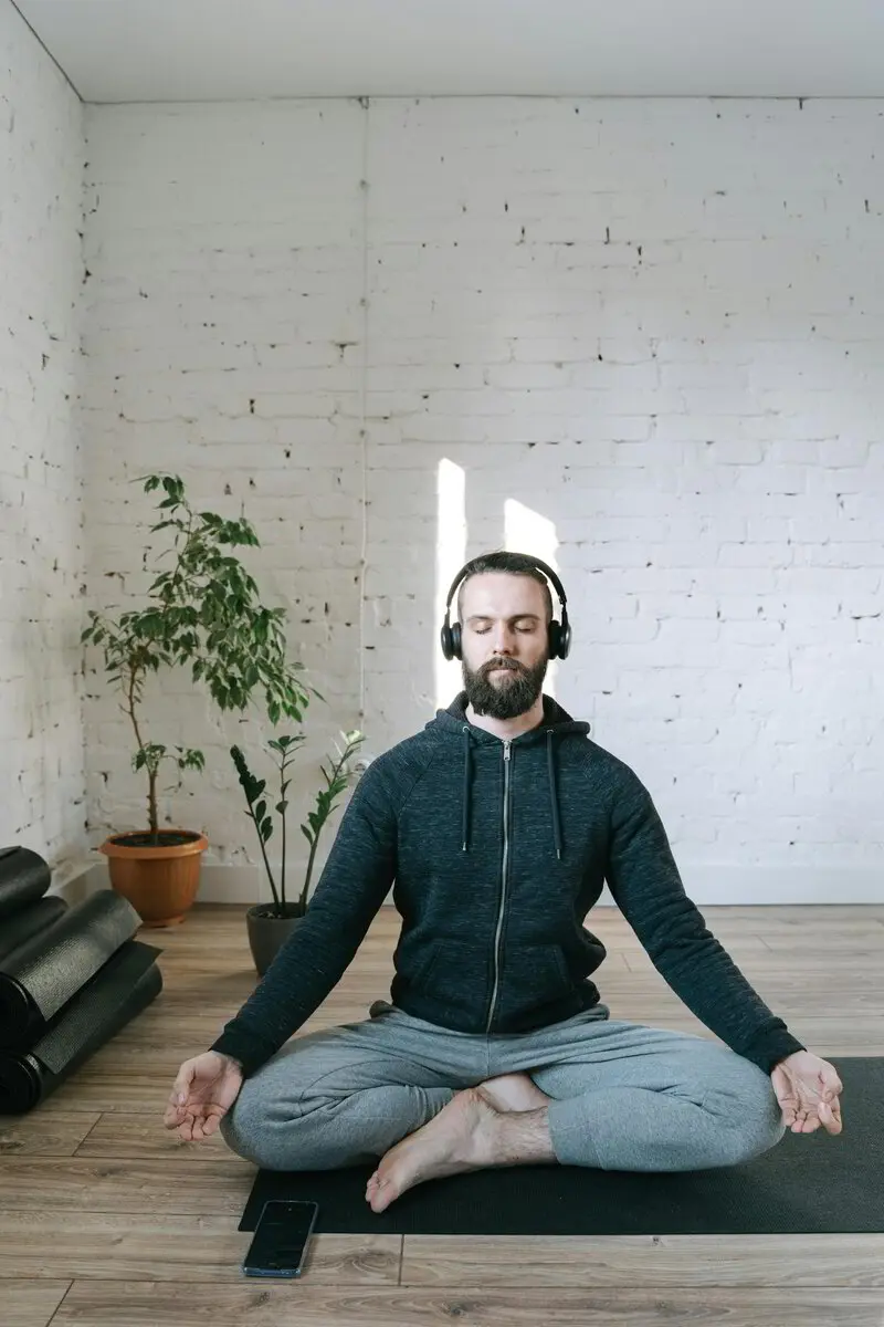 Man meditating on a mat at home
