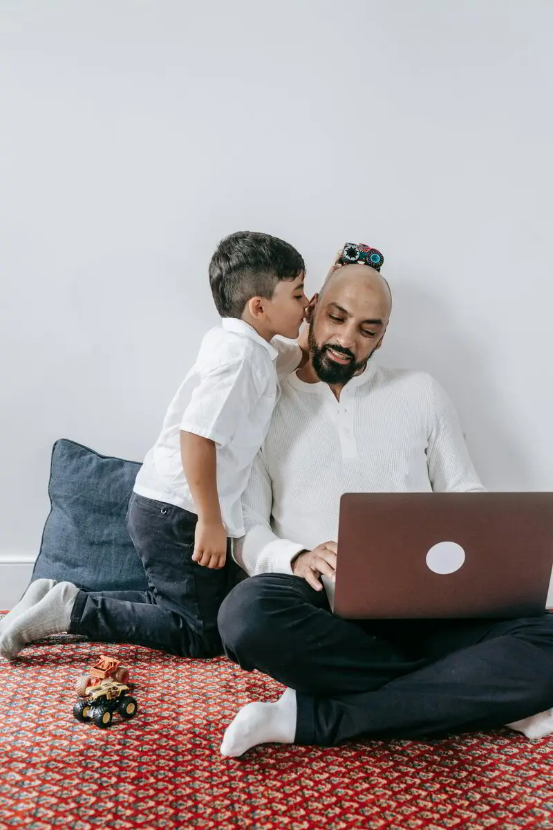 Dad working on a laptop while his kids play nearby