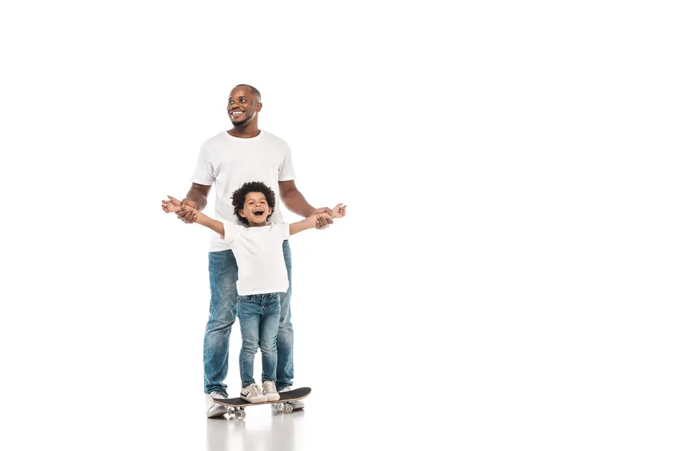 Father helping his young son balance on a skateboard